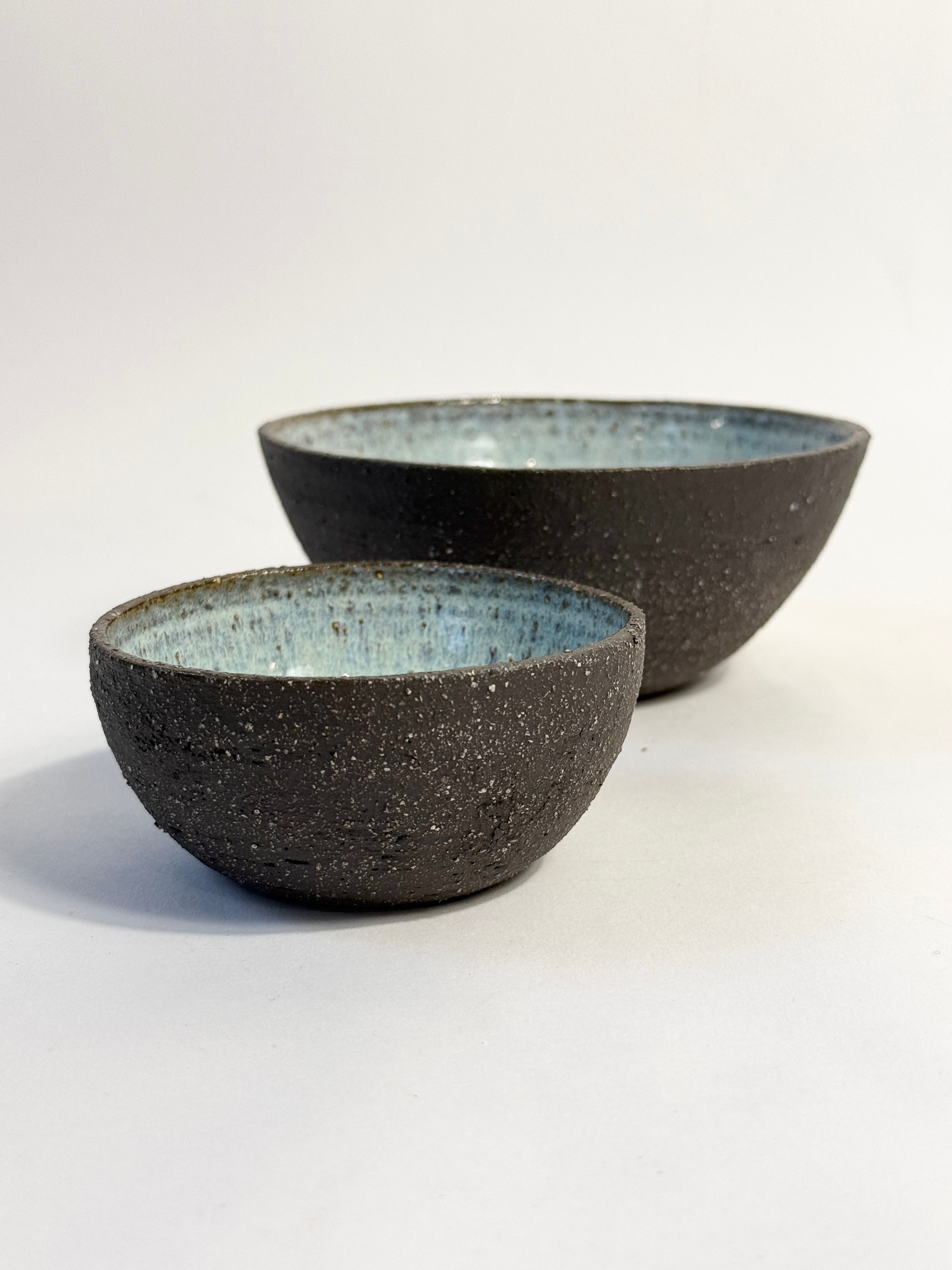 Earthy unglazed exterior bowls showing the natural dark matter clay and glazed interior of pearl blue. 
