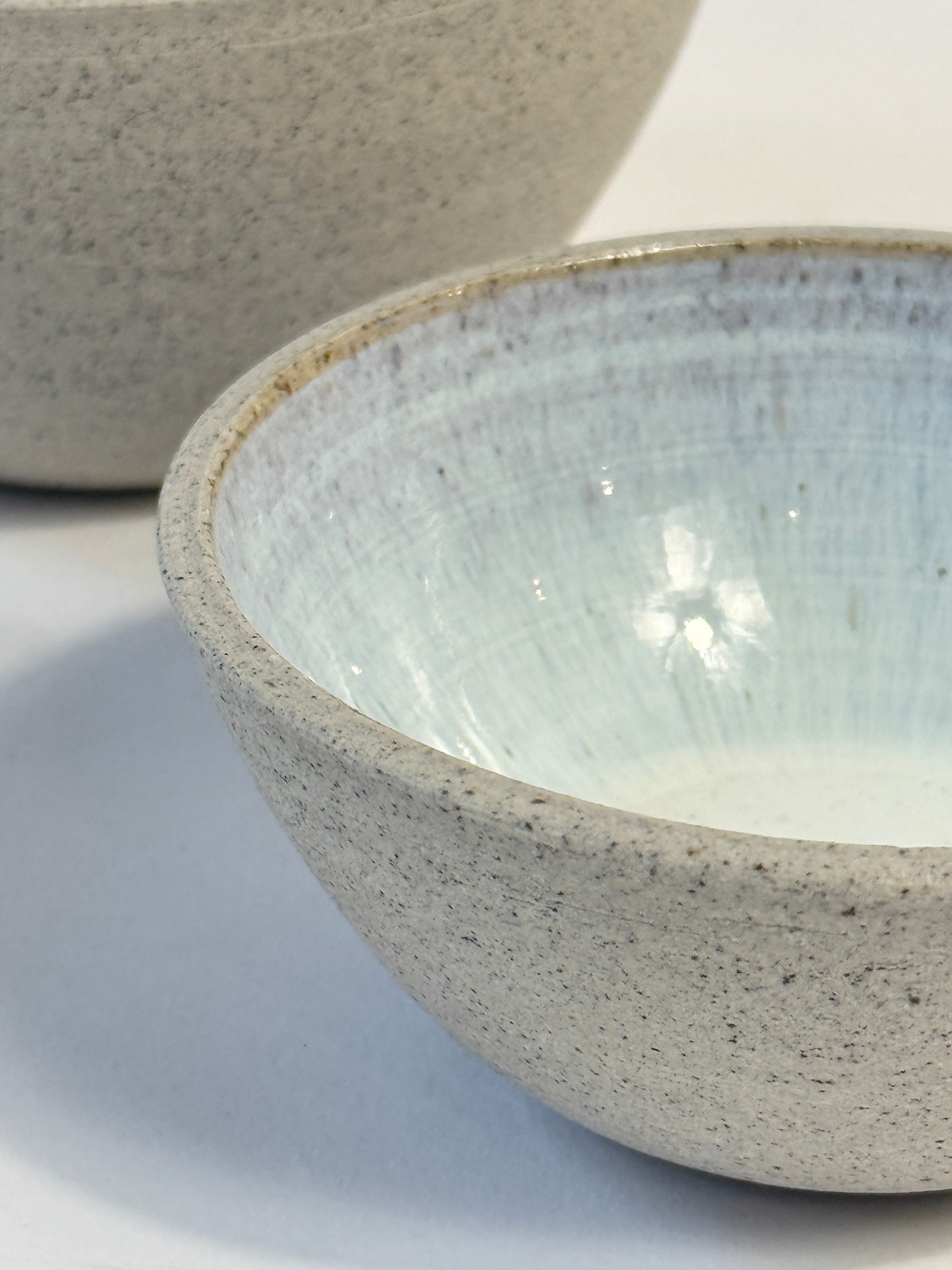 close up of natural clay exterior and light blue glazed interior of unique hand made dish set