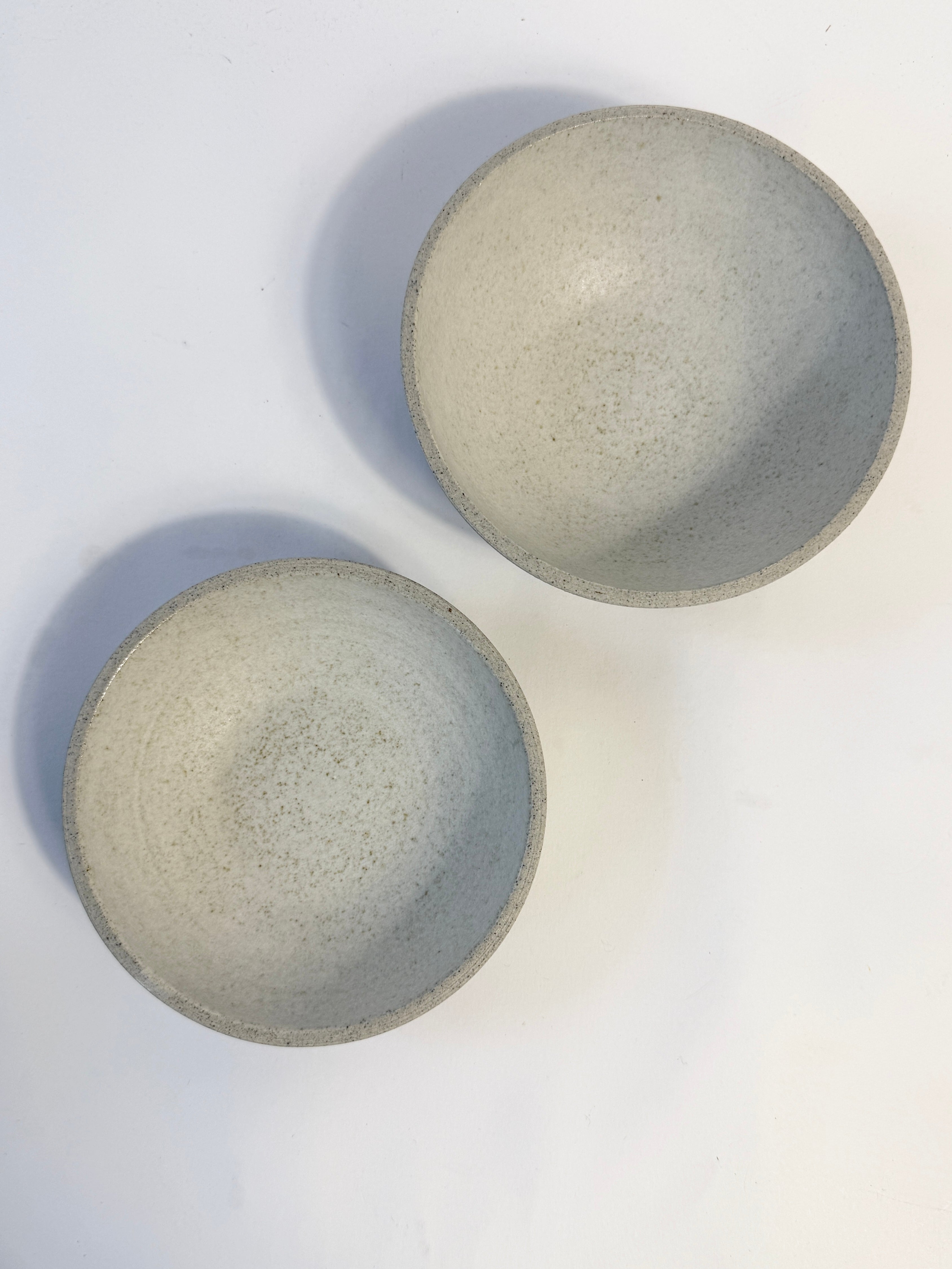 Two handmade ceramic bowls with a speckled light white glaze, photographed from a top-down perspective.  Made in Adelaide South Australia by FionaK